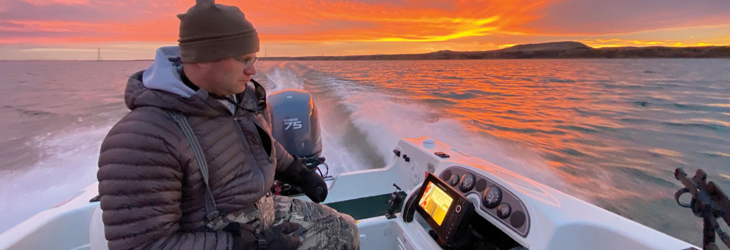 Man on boat with sunset in background