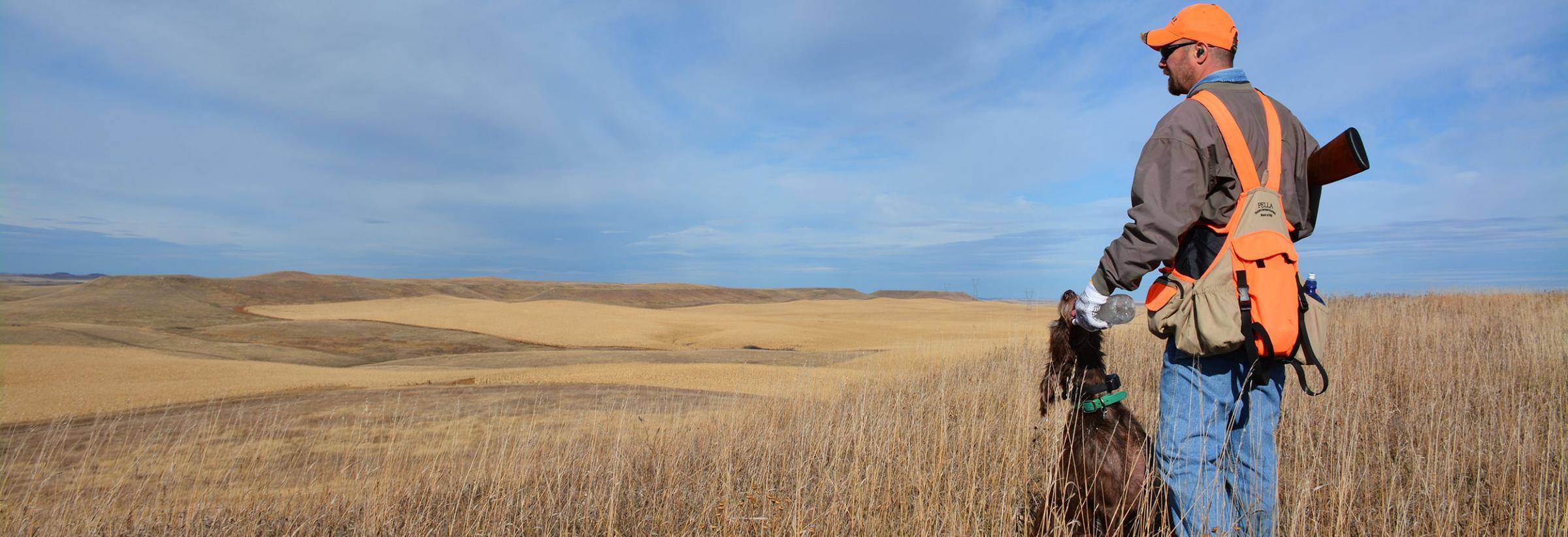 Hunter looking over prairie while giving dog water