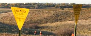 PLOTS sign with hunters in background