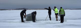 People looking at ice house that went through the ice