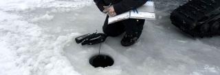 Fisheries staff conducting dissolved oxygen test on frozen lake