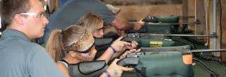Volunteer helping child with air rifle