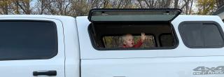 Son waving out a window in the back of the truck