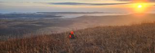 Hunter sitting on hill at sunrise
