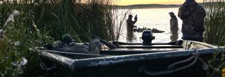 Boat with duck hunters putting out decoys behind