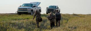 Warden and hunters walking towards trucks