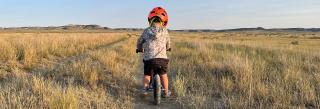Child riding bike down dirt track in the prairie