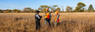 Warden talking to hunters in the field