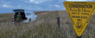 Hunter by truck behind PLOTS sign