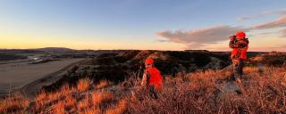 Hunters on a prairie hill looking for deer