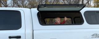 Son waving out a window in the back of the truck