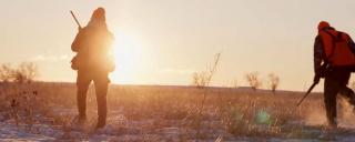 Two hunters with sun behind