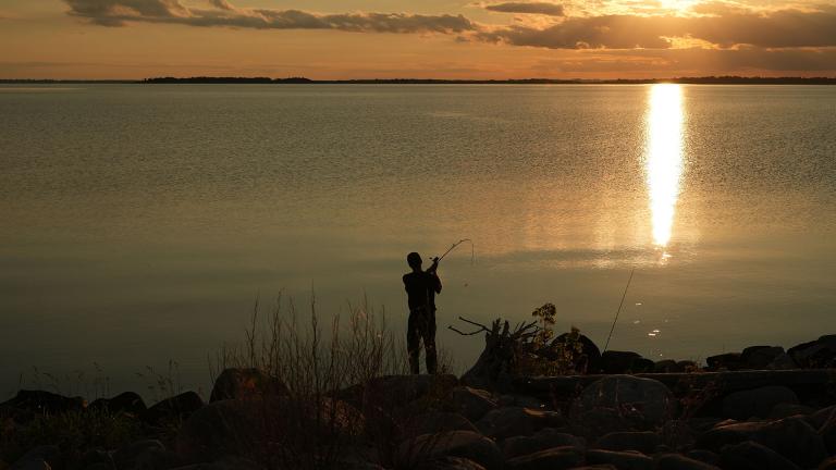 Person shorefishing at sunset