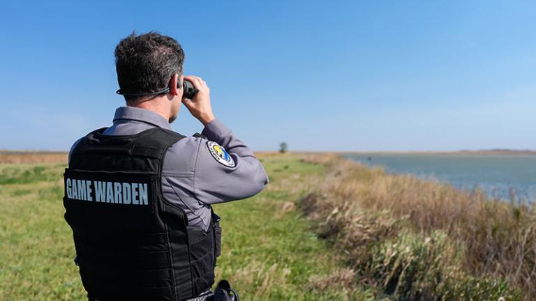 Warden looking at boat in distance