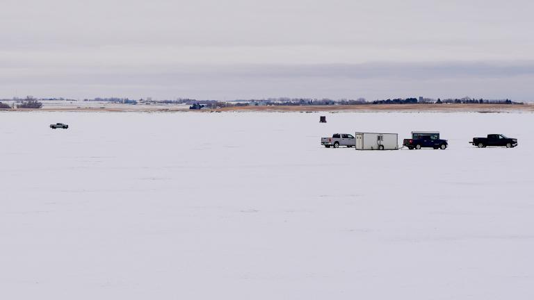 Vehicles and ice houses on frozen lake