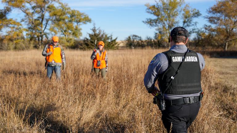 Warden walking towards hunters