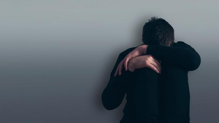 Depressed boy sitting against a wall