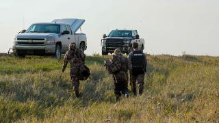 Warden and hunters walking towards trucks