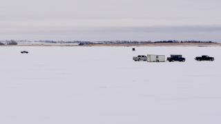Vehicles and ice houses on frozen lake