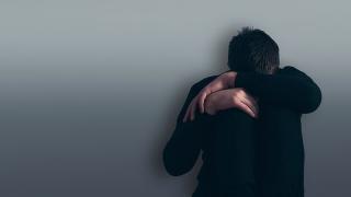 Depressed boy sitting against a wall