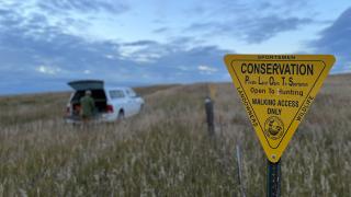 Hunter by truck behind PLOTS sign