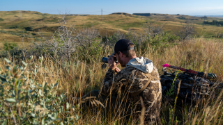 bowhunter glassing with spotting scope in western North Dakota